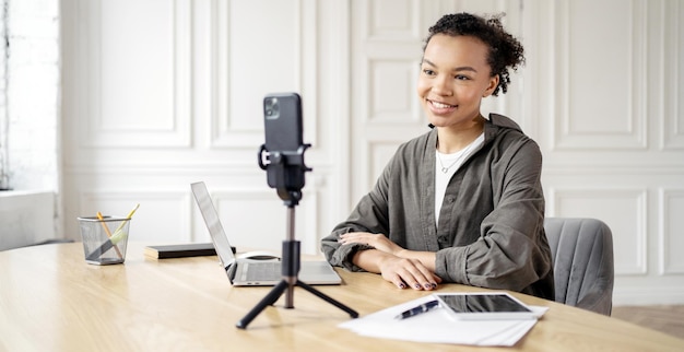 Young female vlogger creating content with smartphone and laptop modern influencer