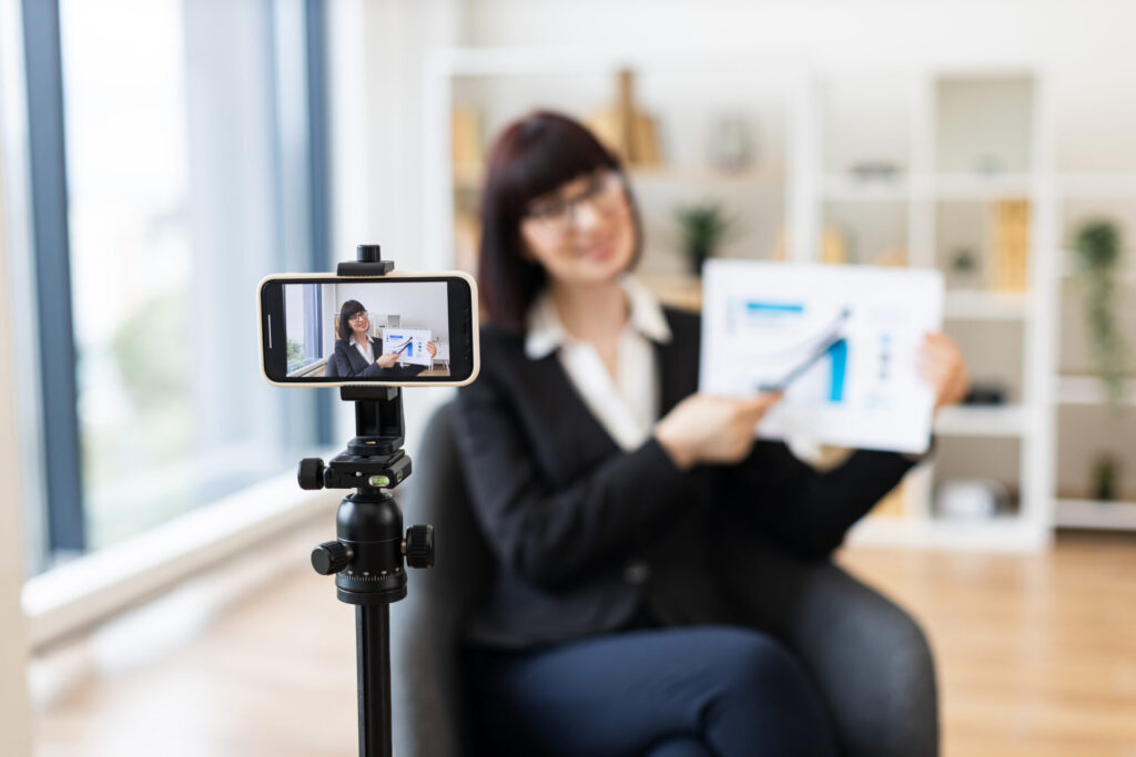 Caucasian woman in business suit recording video about revenue growth using graphs modern office